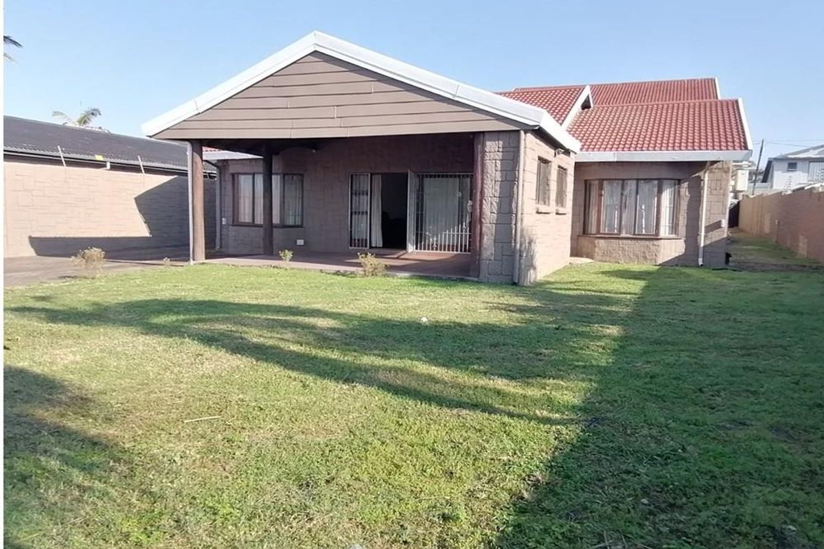 Rear view of the house featuring a covered patio area, tiled roof, and a spacious private garden.