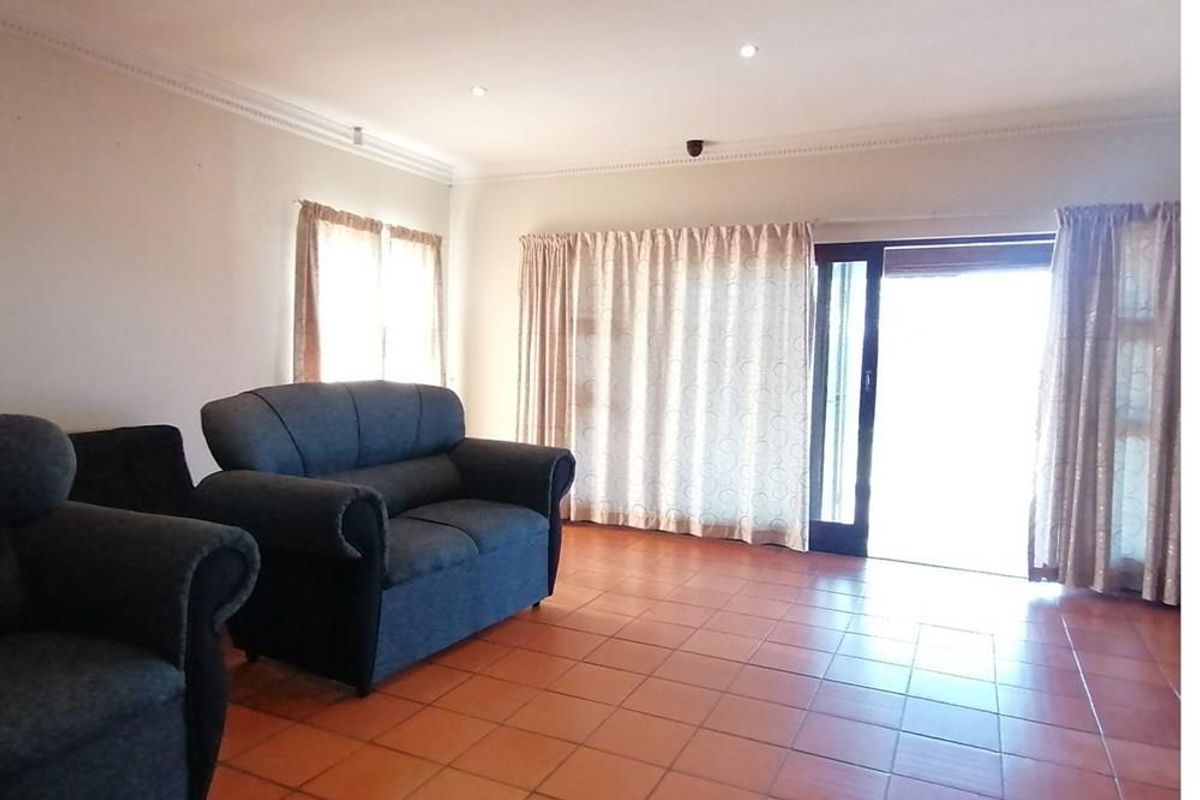 Spacious living room featuring terracotta floor tiles, recessed ceiling lighting, and large sliding glass doors providing access to the outdoor area.