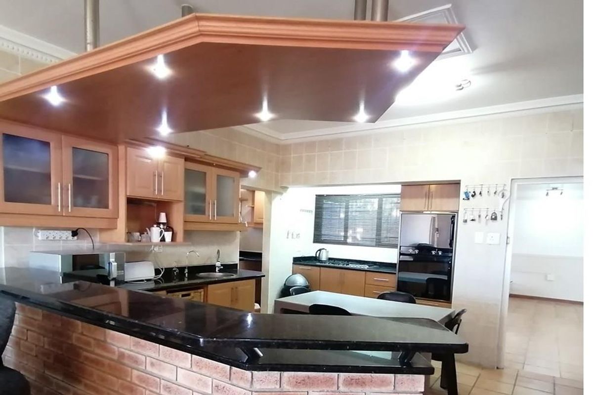 Spacious kitchen featuring a breakfast bar, granite countertops, built-in cabinetry, and integrated oven, offering a functional layout with ample workspace.