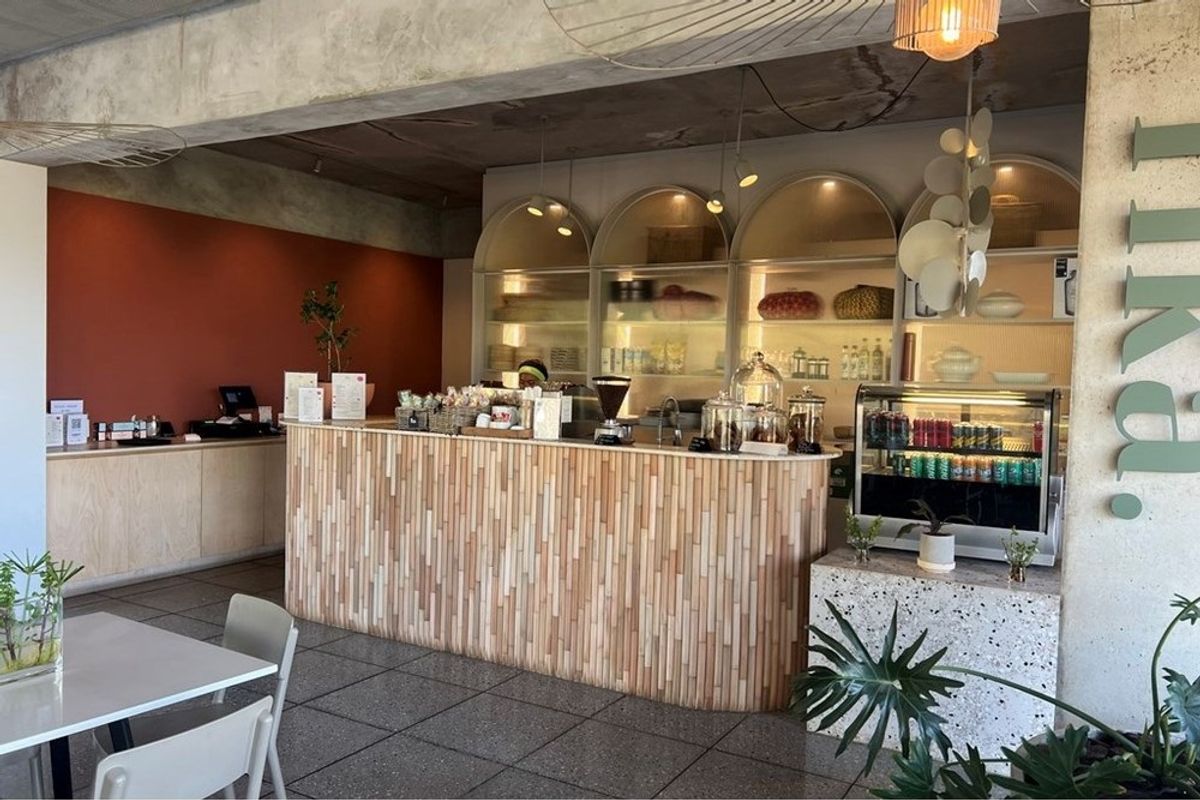 A modern commercial kitchen service counter featuring a textured timber-slat facade, arched display shelving, and polished stone flooring.