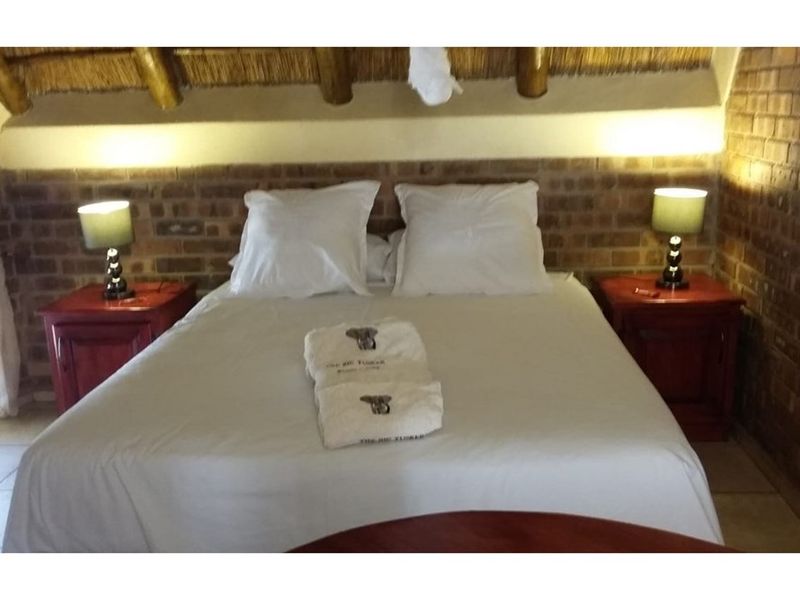 Cozy bedroom featuring rustic exposed brick walls and a traditional thatched roof ceiling, creating a warm and authentic cottage atmosphere.