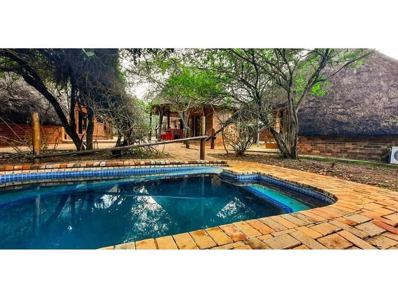 Outdoor pool area featuring brick paving and surrounding cottage-style structures with traditional thatch roofing and brick facades.