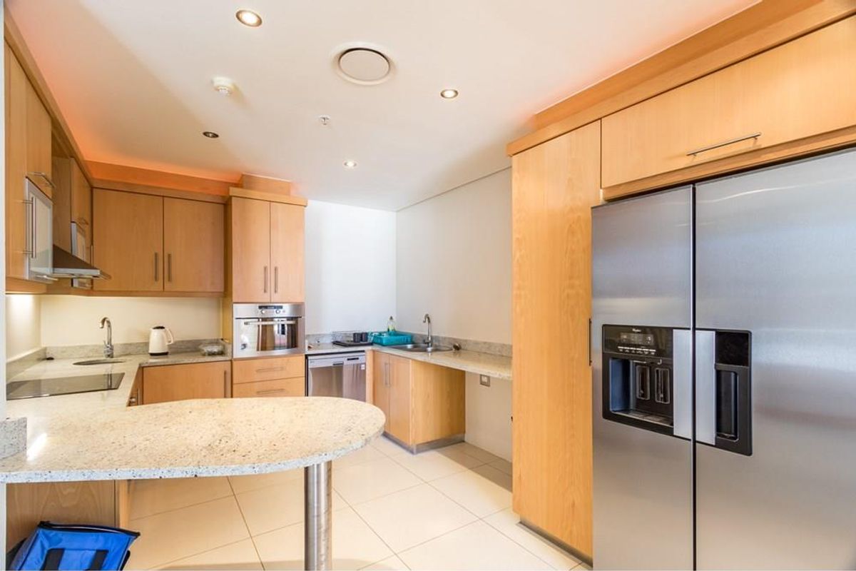 Modern kitchen featuring light wood cabinetry, granite countertops, integrated oven, stainless steel refrigerator, and recessed ceiling lighting.