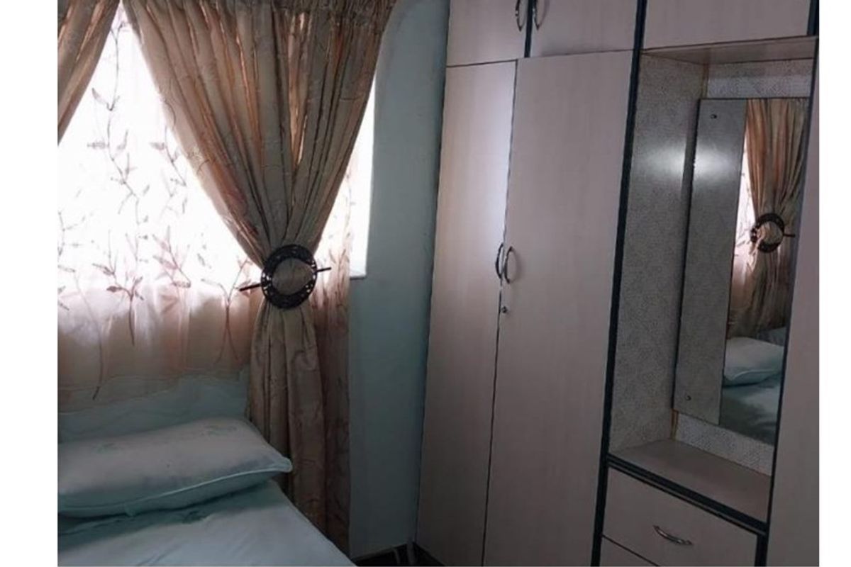 A bedroom featuring a built-in wardrobe with an integrated vanity mirror and storage drawers.