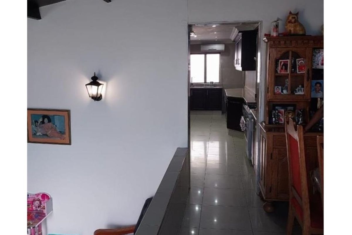 A view from an adjacent living area looking into a kitchen featuring tiled floors, built-in cabinetry, and an integrated air conditioning unit.