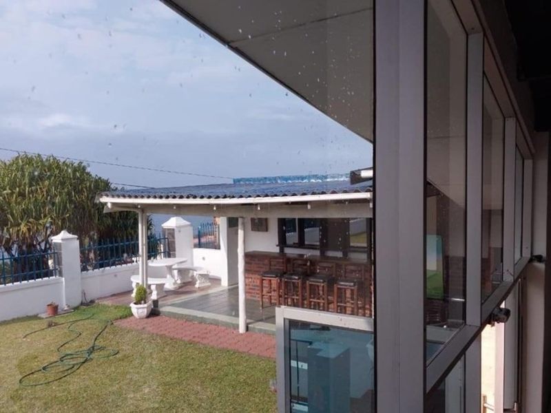 Covered outdoor patio area featuring a built-in brick bar, tiled flooring, and direct access to the garden space.