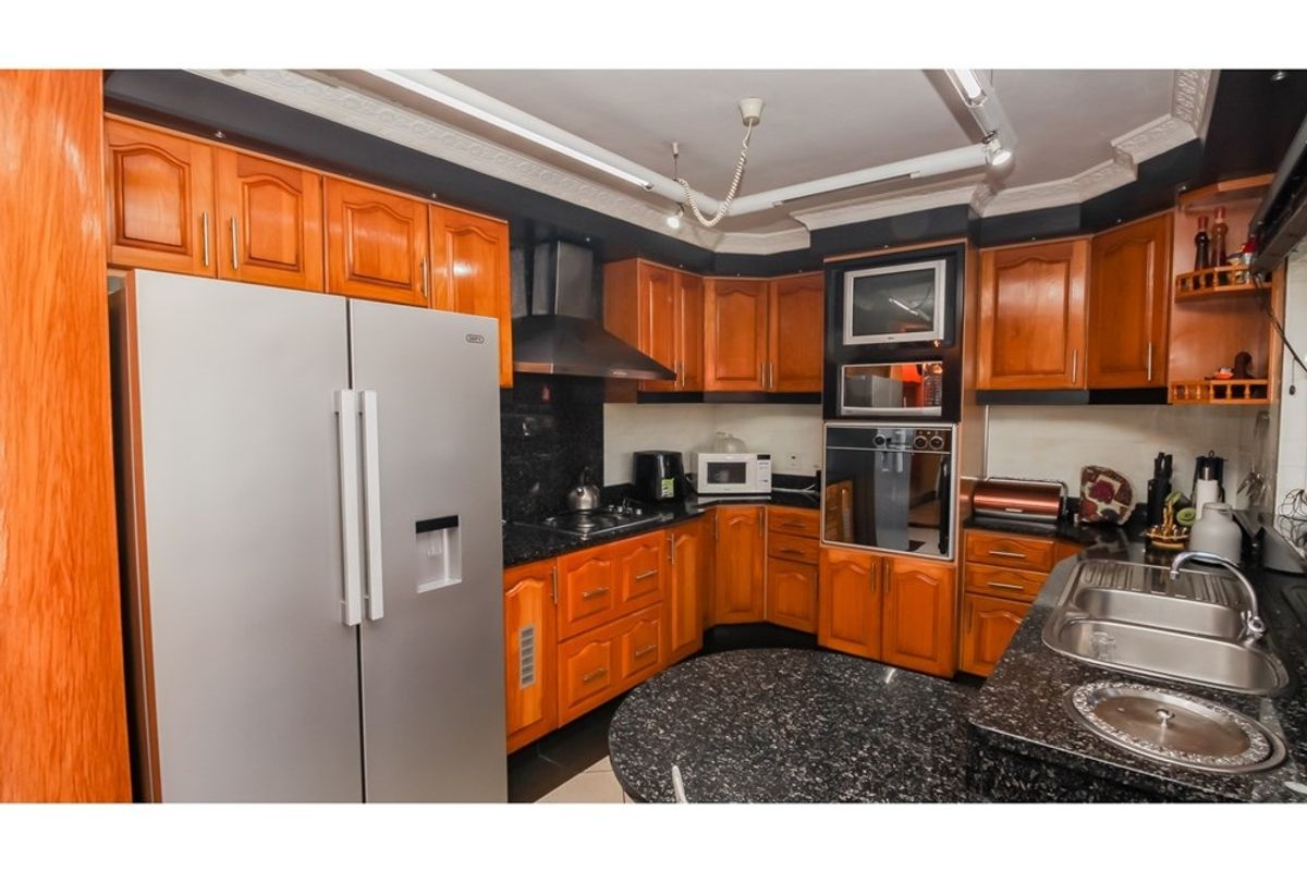 A functional kitchen featuring wooden cabinetry, granite countertops, a built-in oven, and a stainless steel double sink.
