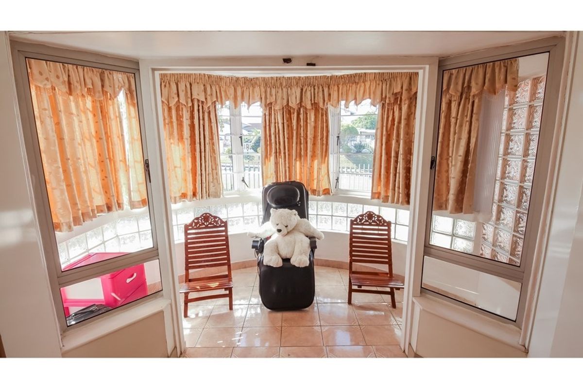 A sunlit bay window area featuring glass block accents and tiled flooring, offering a bright space with views of the front exterior.