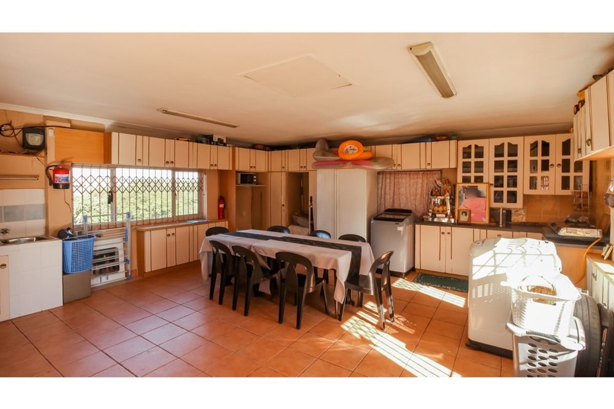 Spacious kitchen featuring extensive built-in cabinetry, tiled flooring, and security bars on windows, offering a functional layout with ample storage space.