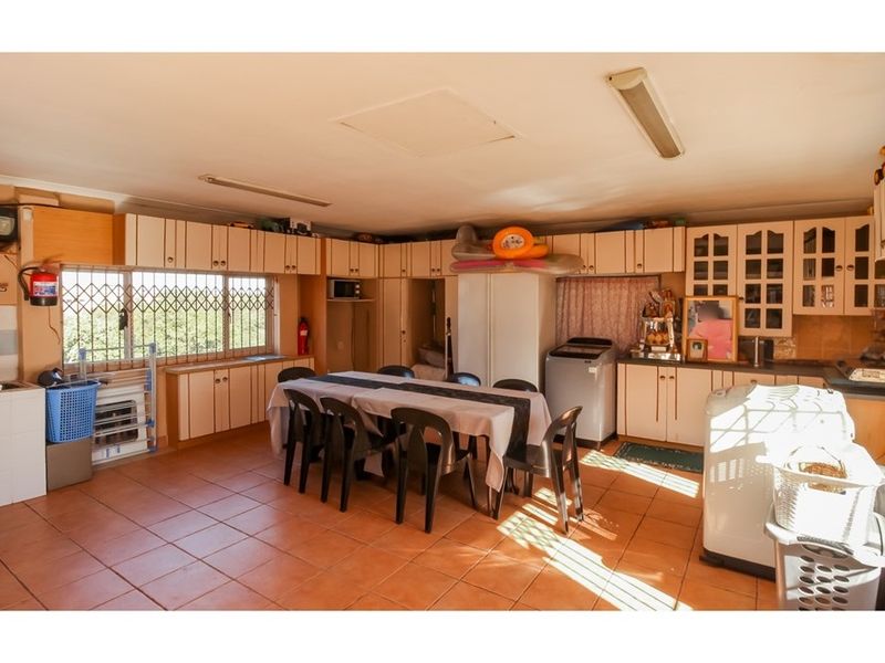 Spacious kitchen featuring extensive built-in cabinetry, tiled flooring, and security bars on windows, offering a functional layout with ample storage space.