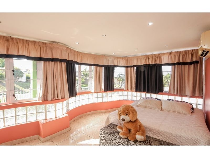 Spacious bedroom featuring unique curved glass block wall detailing, tiled flooring, recessed lighting, and an integrated air conditioning unit.