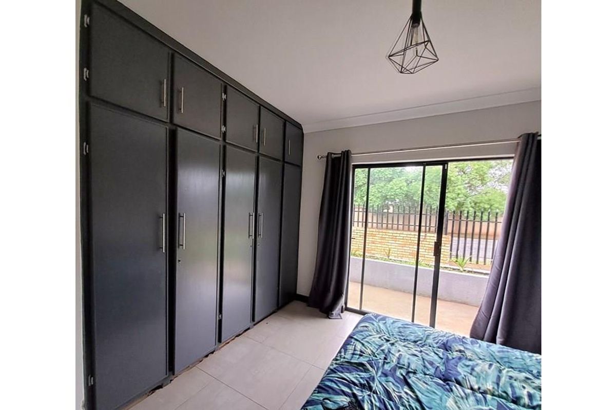 Bedroom featuring floor-to-ceiling built-in cupboards, tiled flooring, and sliding glass doors providing direct access to the outdoor patio area.