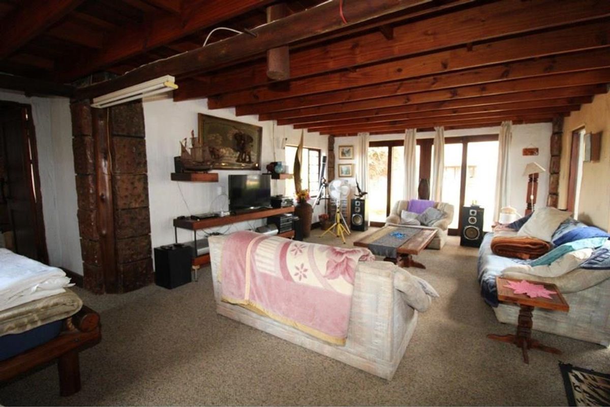 Spacious living area featuring exposed timber ceiling beams, large glass sliding doors providing natural light, and rustic structural timber accents.