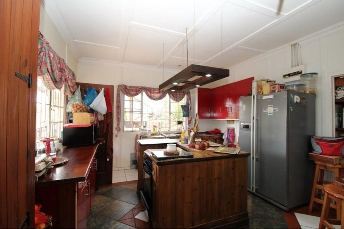 A functional kitchen featuring a central wooden island, red cabinetry, and tiled flooring, providing a practical workspace with integrated lighting.