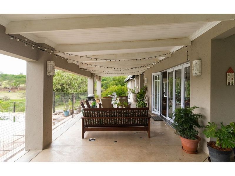 A spacious covered patio featuring a concrete floor, exposed beam ceiling, and large glass sliding doors providing access to the interior living space.