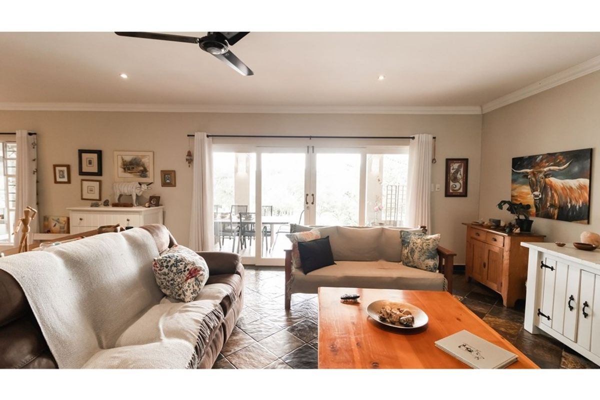 Spacious living room featuring tiled flooring, a ceiling fan, and large sliding glass doors that provide direct access to the outdoor patio area.