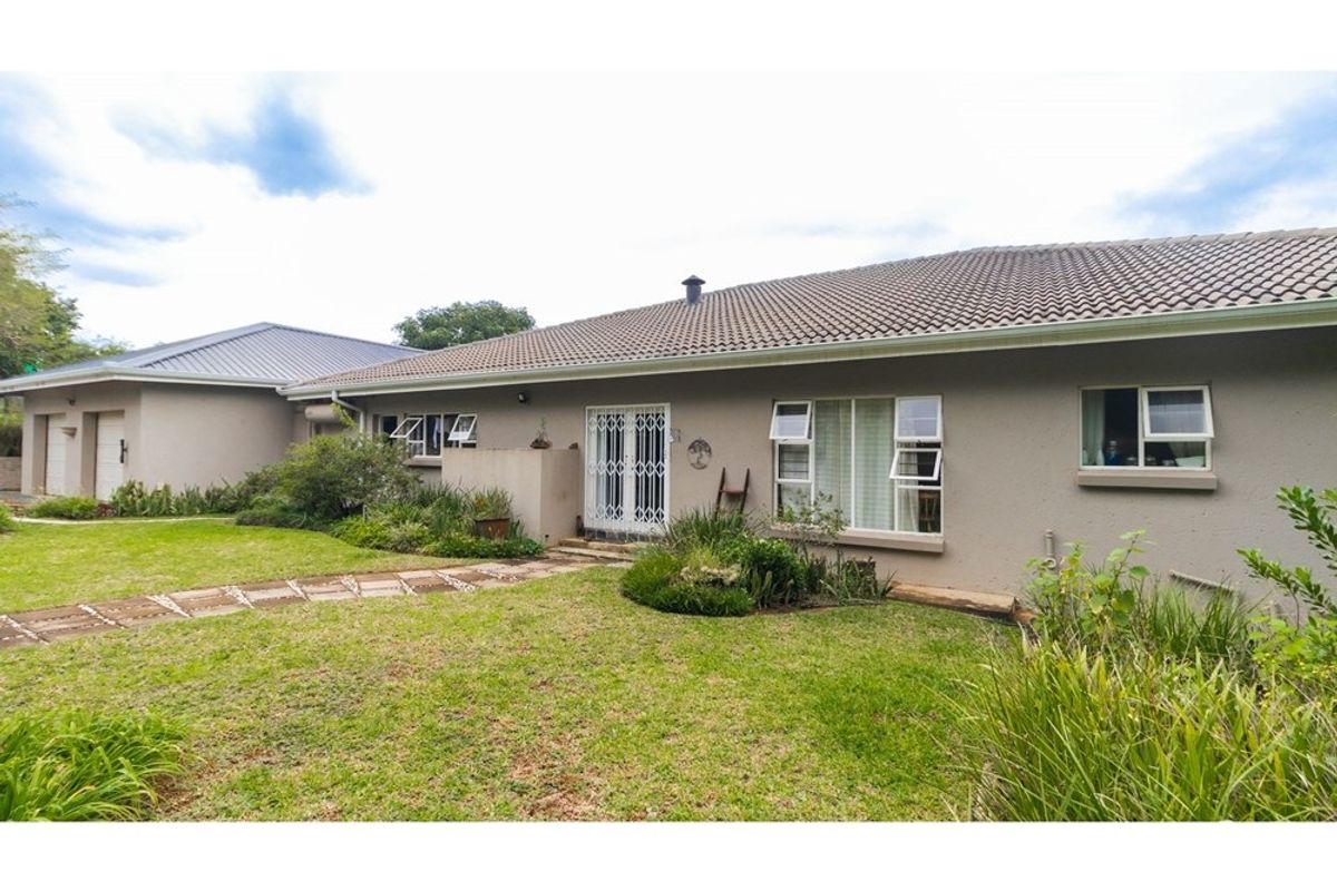 Rear view of the property featuring a tiled roof, plastered exterior walls, security gates, and a well-maintained garden area.