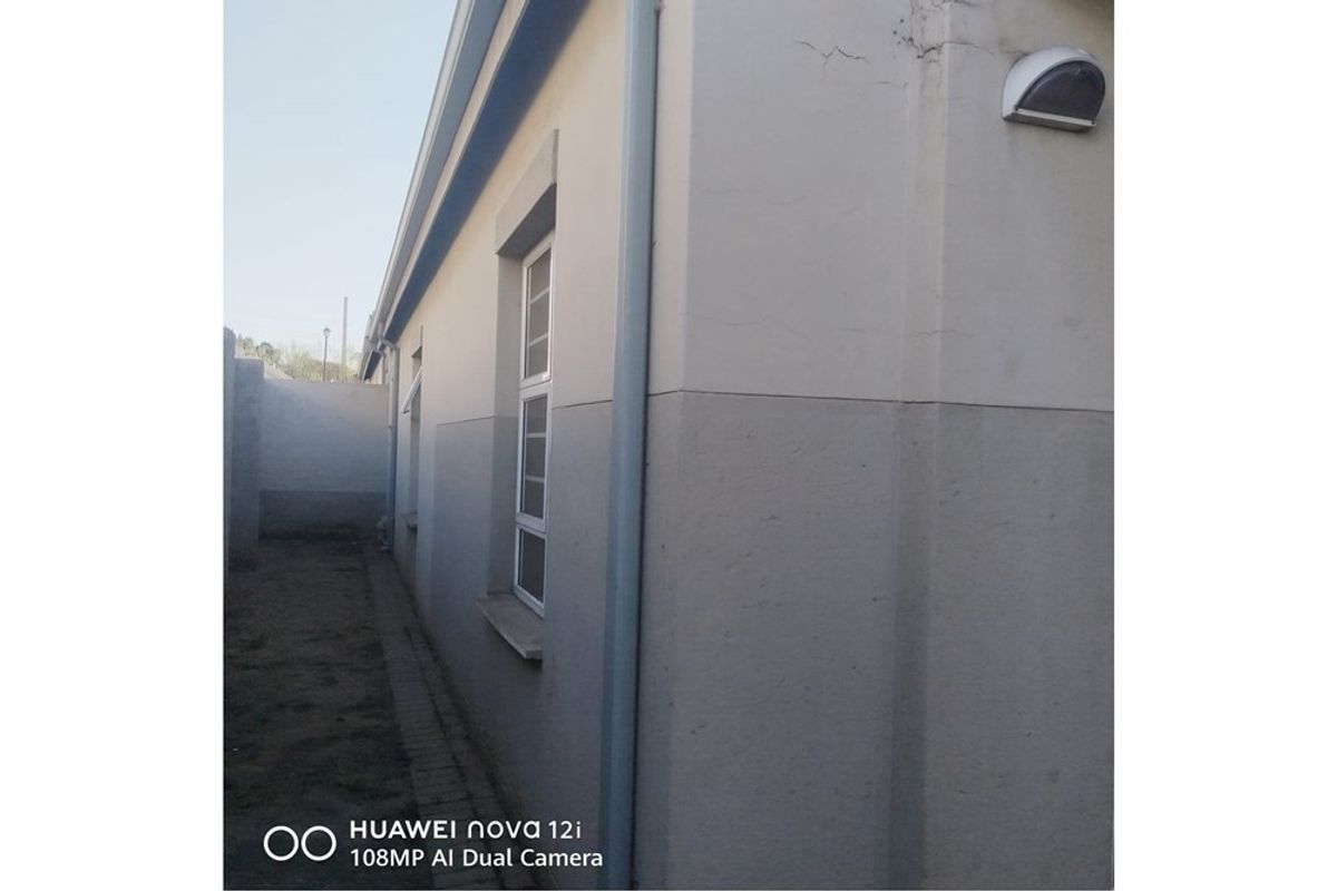Side view of the property exterior showing a downpipe, window, and visible cracking in the exterior wall plaster.