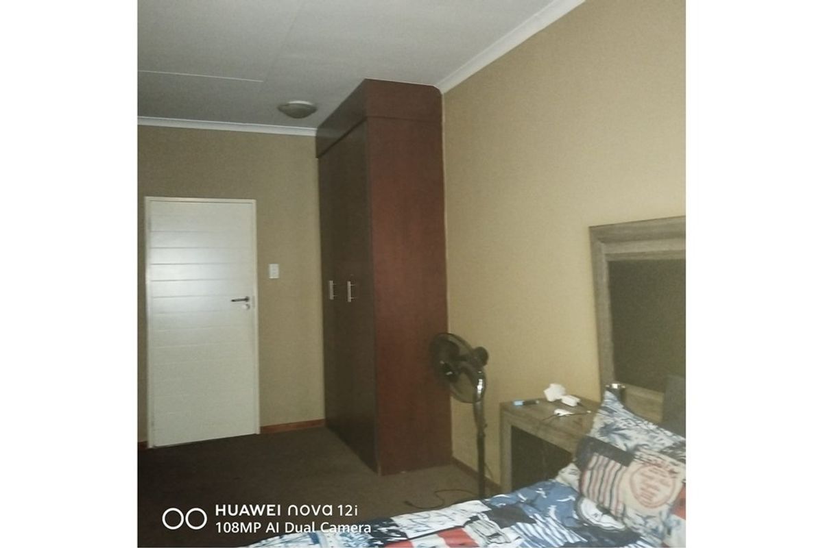 A bedroom featuring a built-in wooden wardrobe and neutral wall finishes.