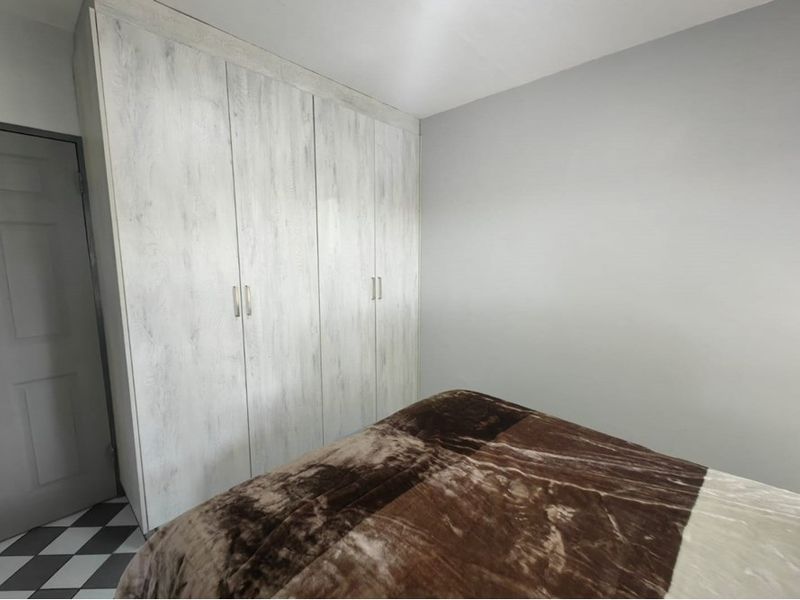 A bedroom featuring light-toned wood-grain built-in wardrobes and neutral wall finishes.