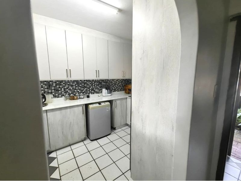 A functional laundry room featuring built-in cabinetry, a mosaic tile backsplash, and durable ceramic floor tiles.