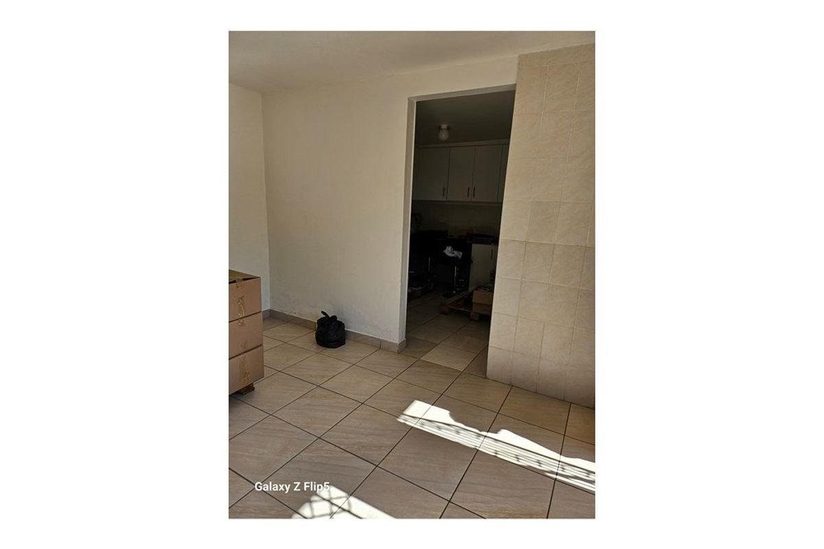 An interior view showing a tiled living area with a doorway leading into a kitchen space.