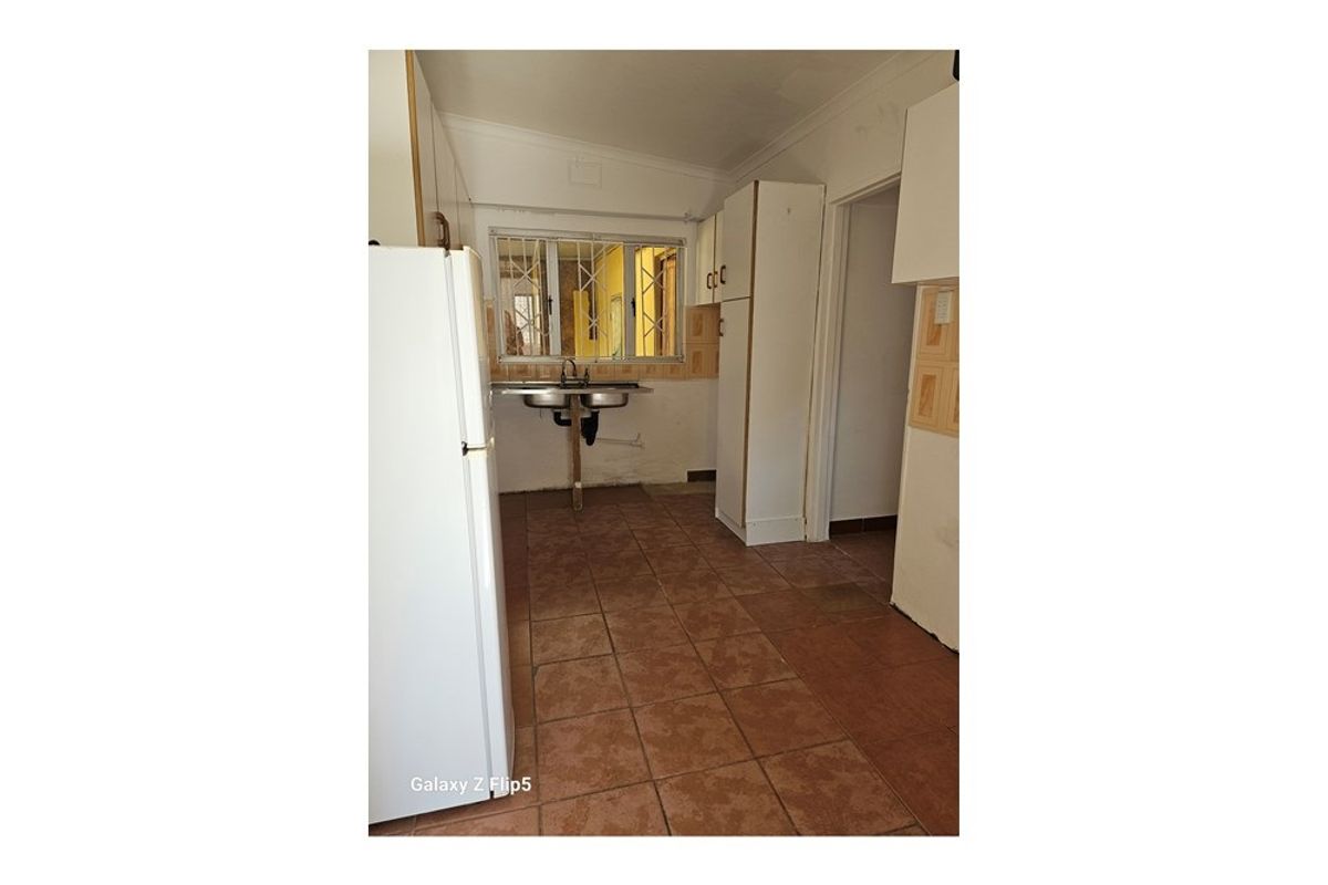 A functional kitchen space featuring tiled flooring, built-in cabinetry, and a double-basin sink with a window view.