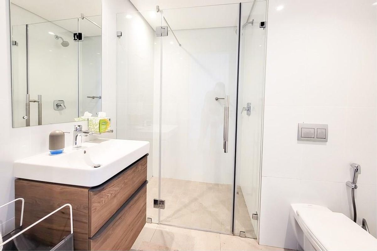 Modern bathroom featuring a glass-enclosed shower, wall-mounted toilet, and a contemporary vanity with integrated basin and storage.