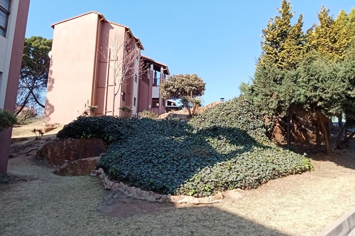 Exterior view of the apartment building complex featuring landscaped garden areas with mature trees and established ground cover.