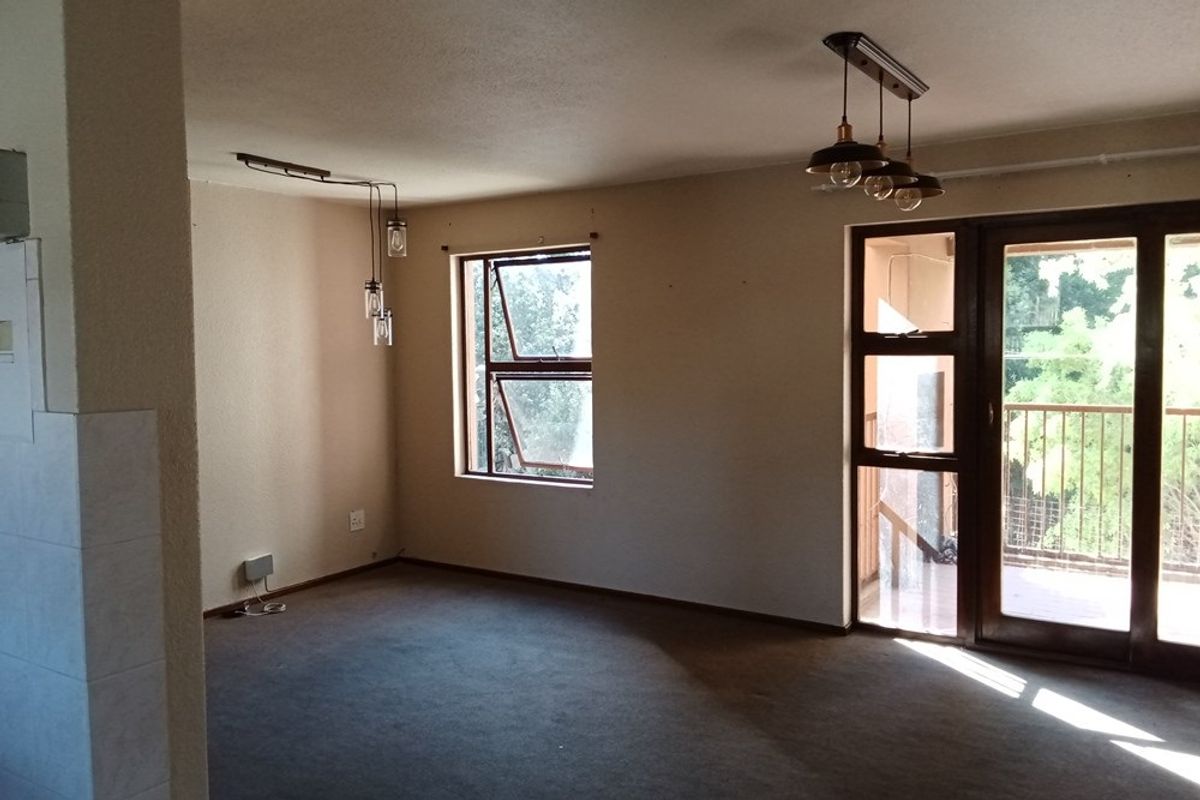 Spacious living area featuring large windows, glass sliding doors leading to a balcony, and modern pendant lighting fixtures.