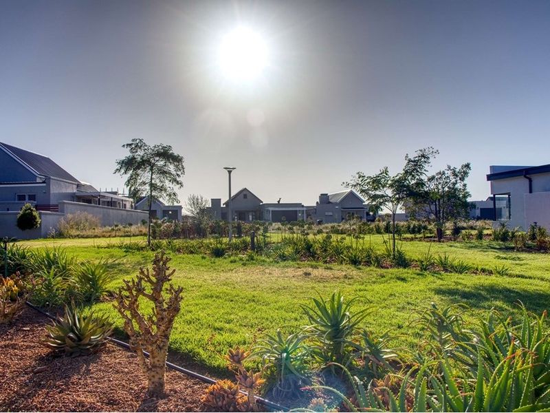 A well-maintained residential garden featuring established landscaping, lawn areas, and integrated outdoor lighting within a secure estate setting.