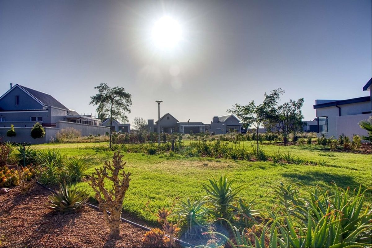 A well-maintained residential garden featuring established landscaping, lawn areas, and integrated outdoor lighting within a secure estate setting.