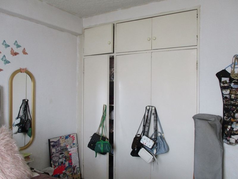 A bedroom featuring a built-in wardrobe with overhead storage cupboards, providing functional storage space within the room.