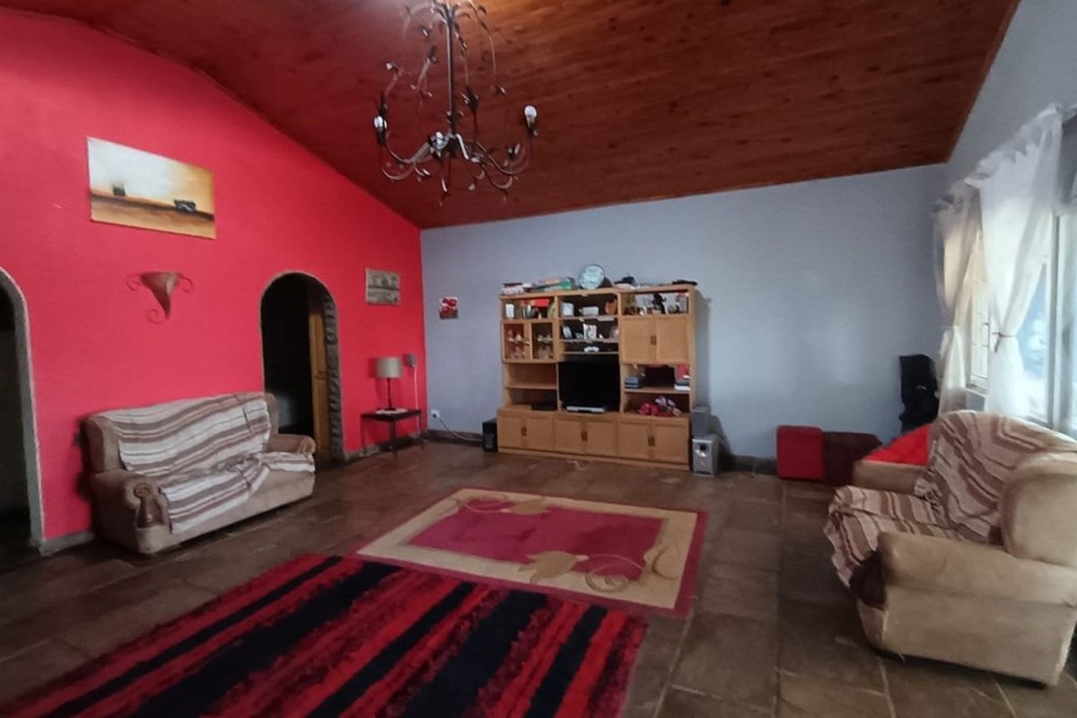 Spacious living room featuring a vaulted timber ceiling, tiled flooring, and arched doorways, providing a traditional and open living environment.