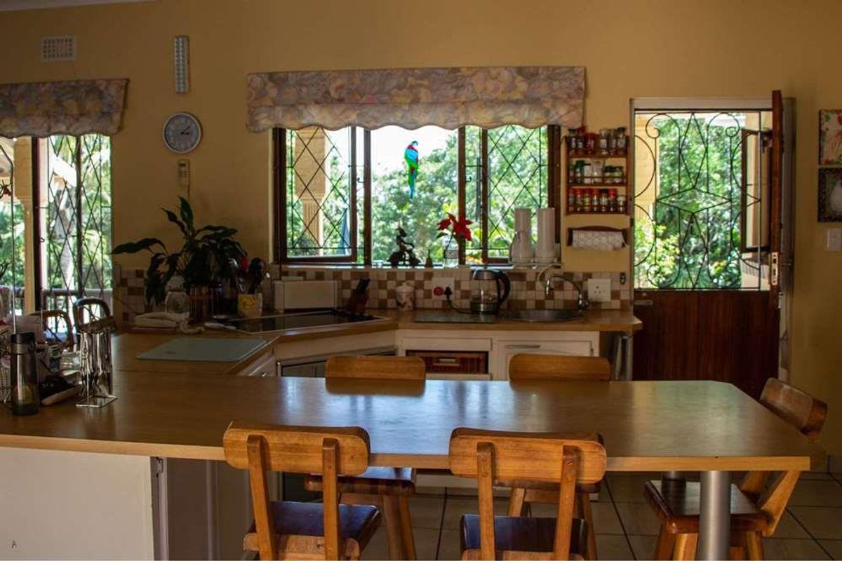 A functional kitchen featuring built-in cabinetry, a tiled backsplash, and a breakfast bar, with direct access to an outdoor area through a security gate.