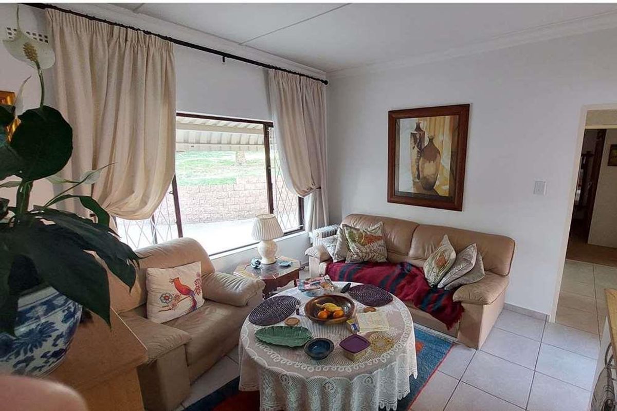 A cozy living room featuring tiled flooring and a large window with security gate, offering a bright and functional space.