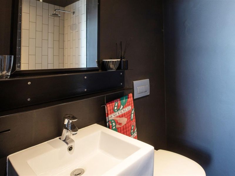 Modern bathroom featuring a wall-mounted basin, chrome fixtures, and a shower enclosure with white subway tiling and dark accent walls.