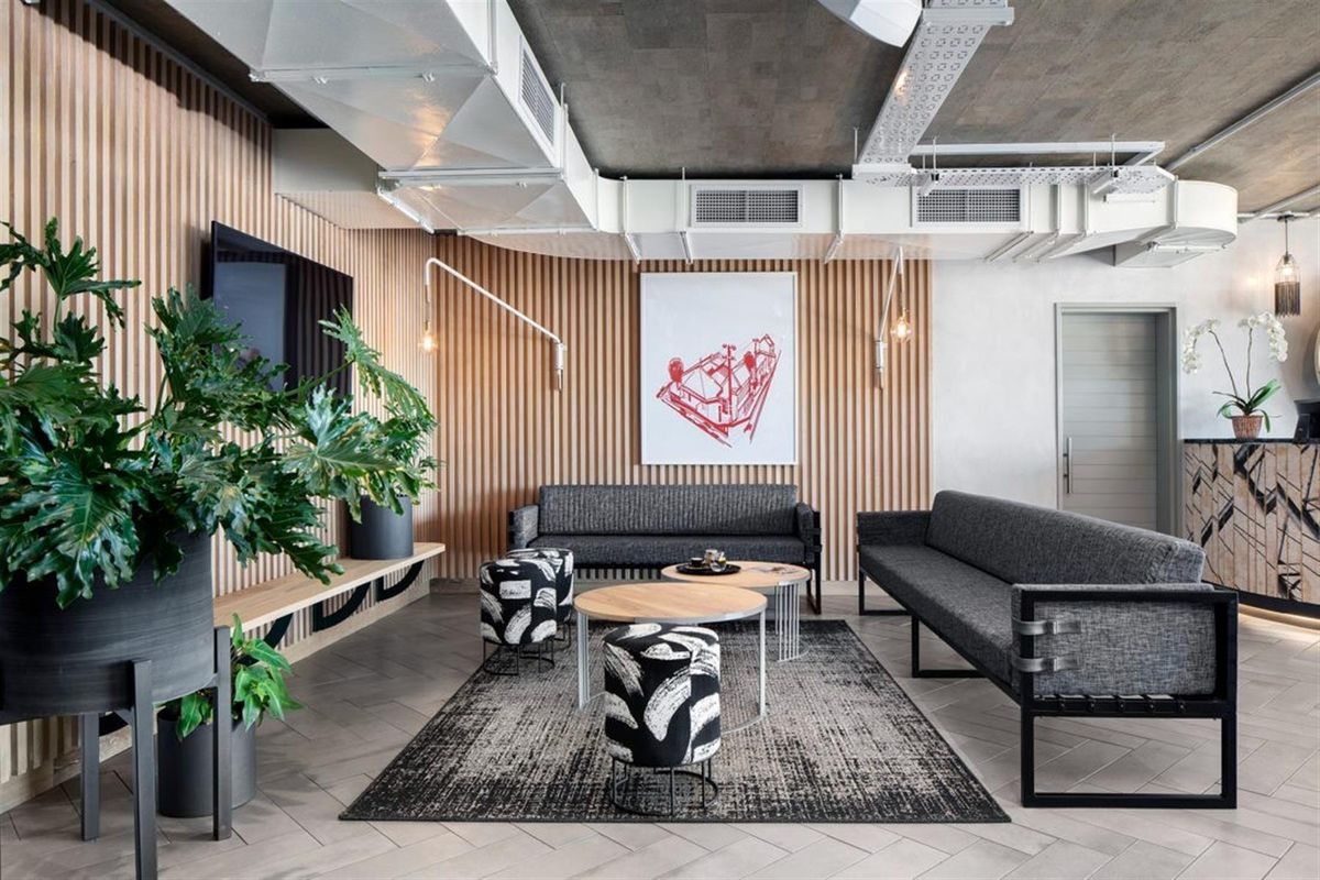 Modern living area featuring stylish timber slat wall paneling, exposed industrial ceiling with HVAC ducting, and contemporary tiled flooring.