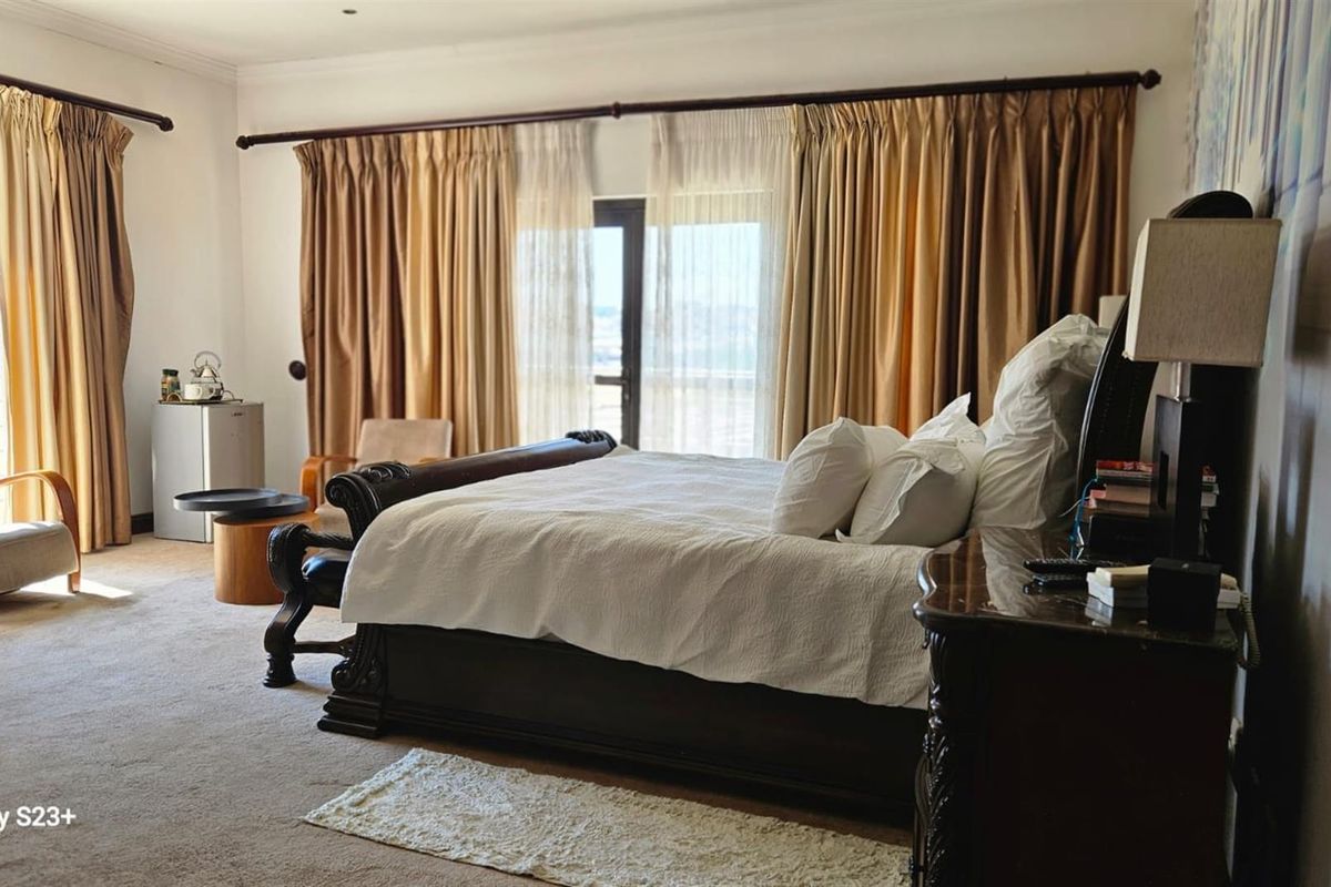 Spacious bedroom featuring neutral carpeting, large windows with floor-to-ceiling curtains, and direct access to an outdoor balcony area.