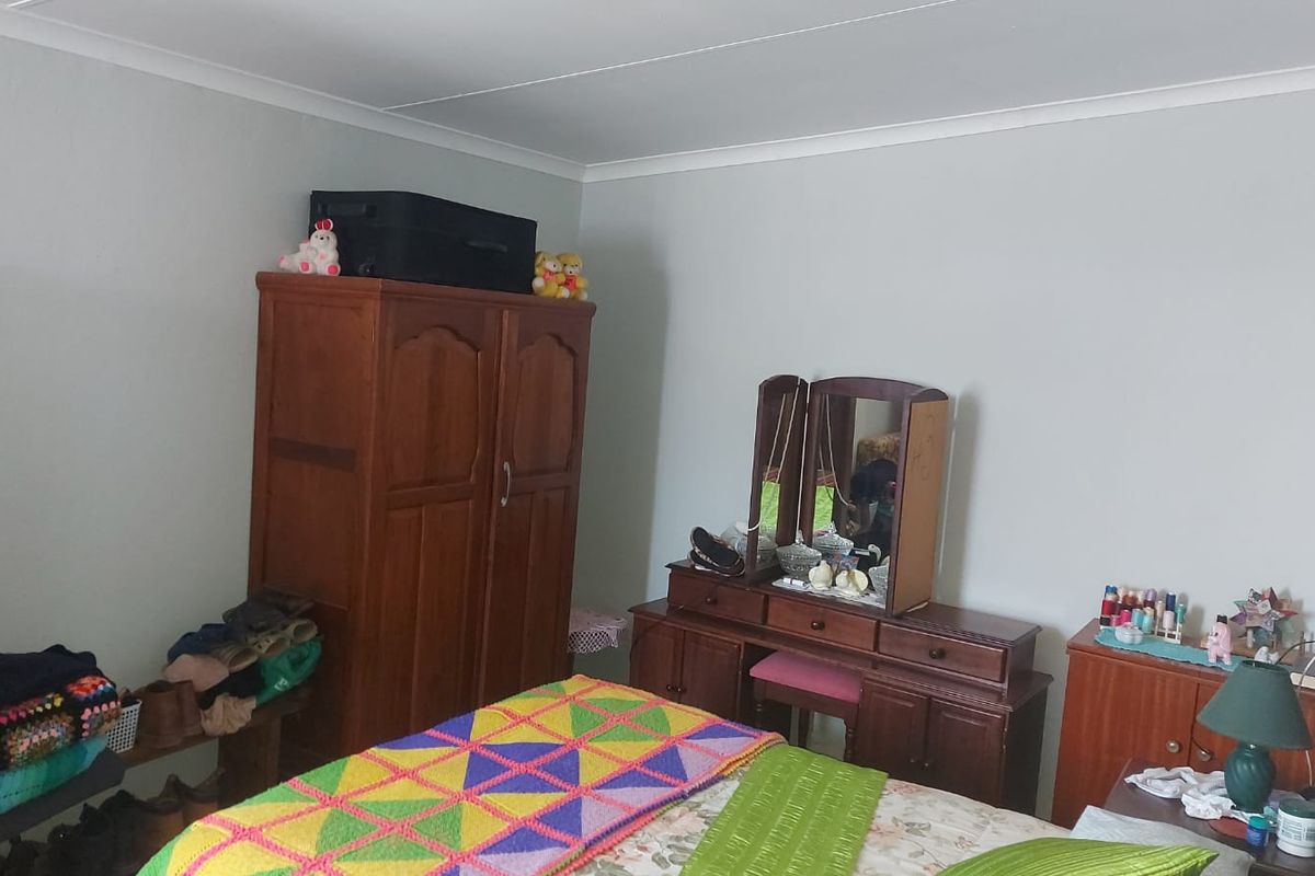 A standard bedroom featuring neutral wall paint, coved ceiling cornices, and carpeted flooring.