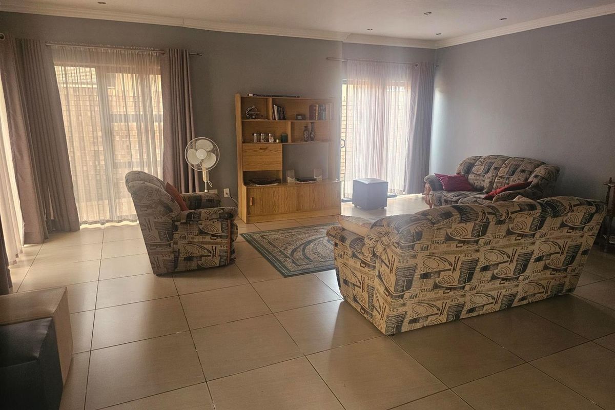 Spacious living room featuring large format floor tiles, recessed ceiling lighting, and dual sliding glass doors providing ample natural light.