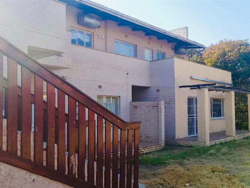Rear view of the property featuring a covered patio, brick facade, and an external wooden staircase leading to the upper level.