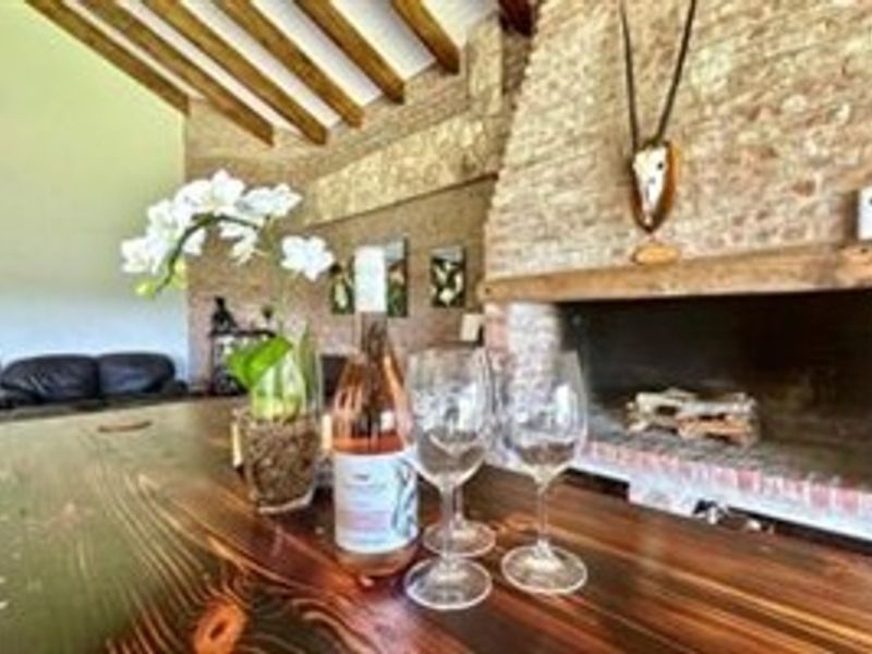 Rustic living area featuring a prominent brick fireplace with a timber mantelpiece and exposed wooden ceiling beams.