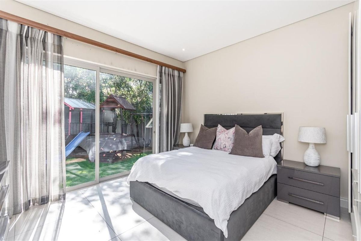 A bright bedroom featuring large sliding glass doors that provide direct access to the rear garden area.