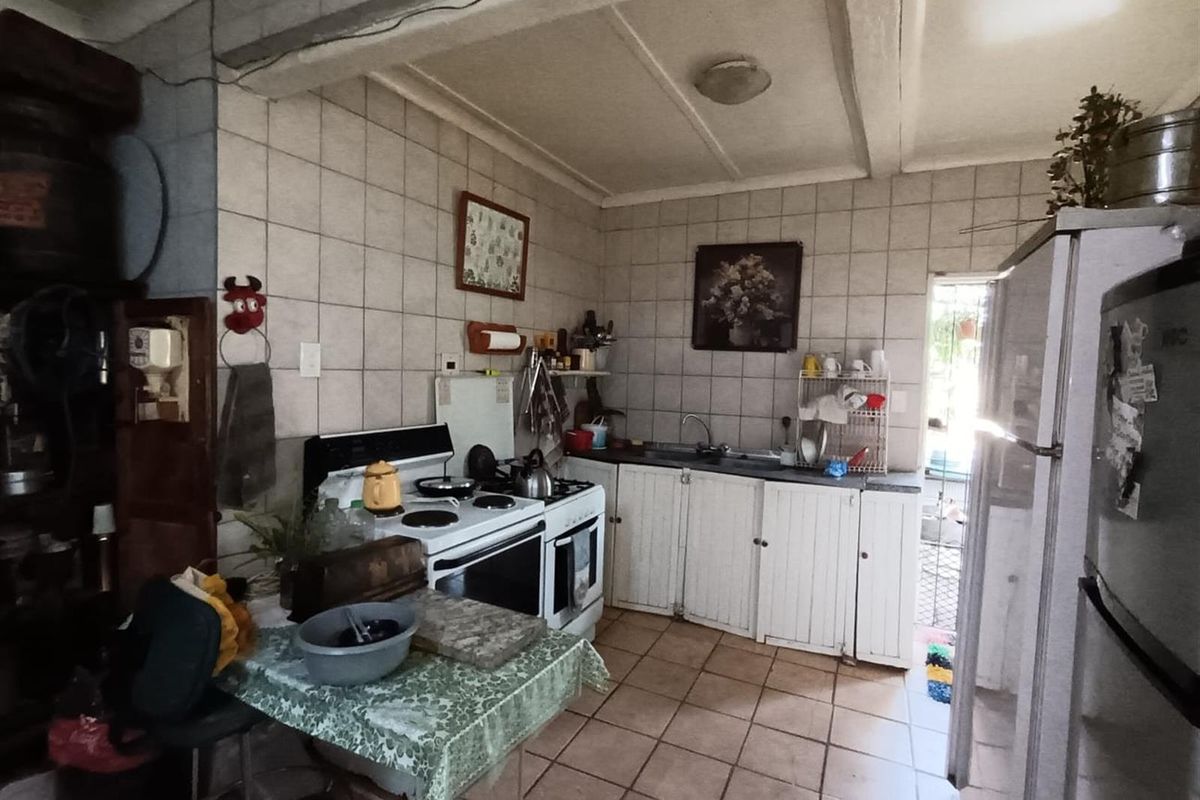 A functional kitchen featuring tiled flooring, wall-mounted cabinetry, and a freestanding stove, offering a practical layout with direct access to an outdoor area.