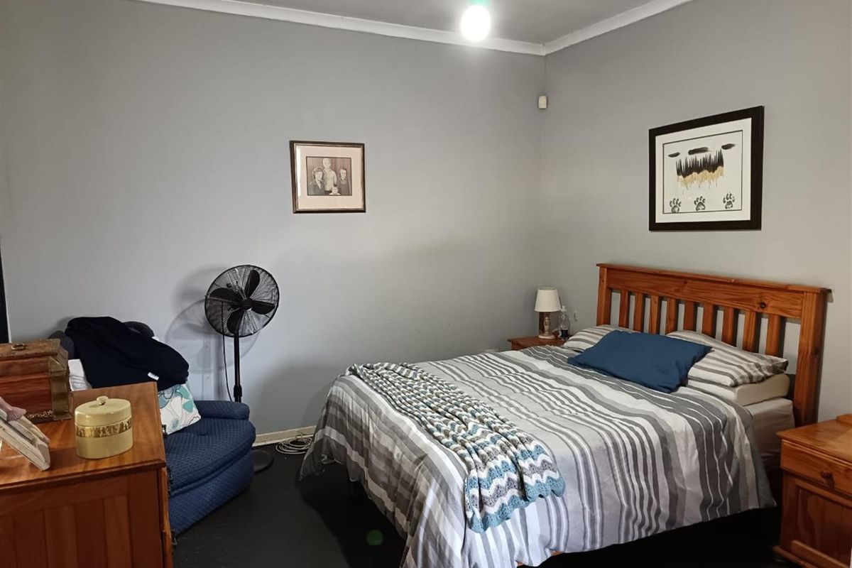 A standard bedroom featuring painted walls, a ceiling light fixture, and dark flooring.