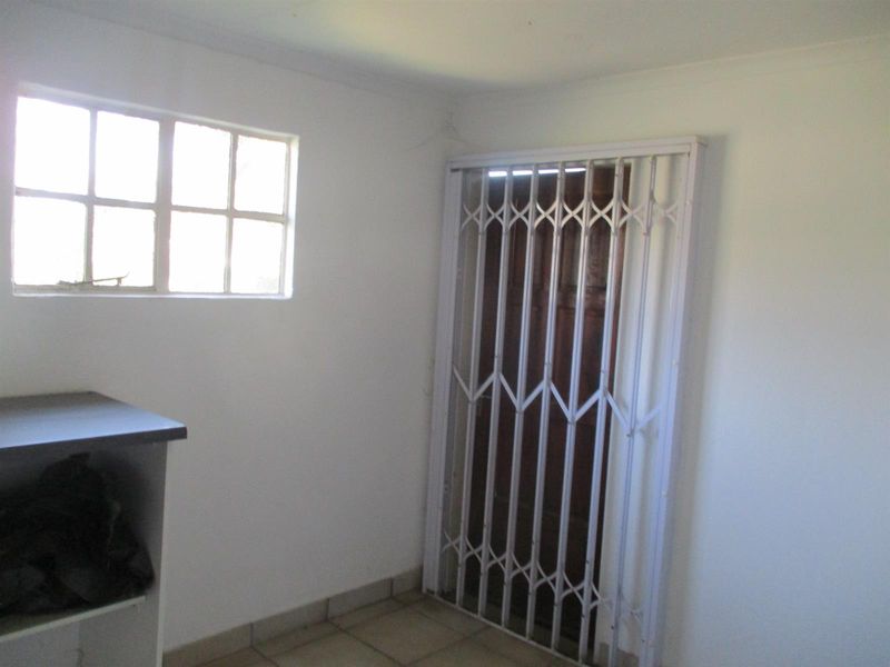 A functional utility space featuring tiled flooring, a built-in counter, and a secure metal gate over the doorway.