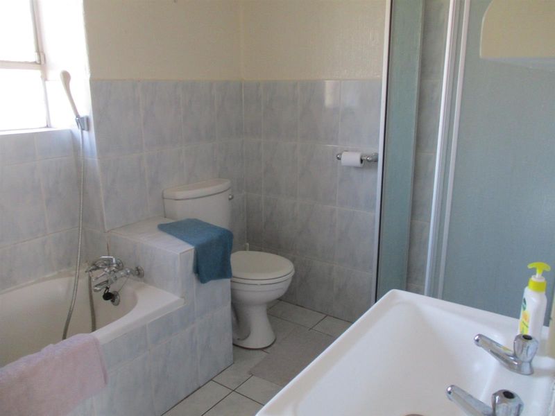A functional bathroom featuring a built-in bathtub, separate shower enclosure, toilet, and pedestal basin with tiled finishes.