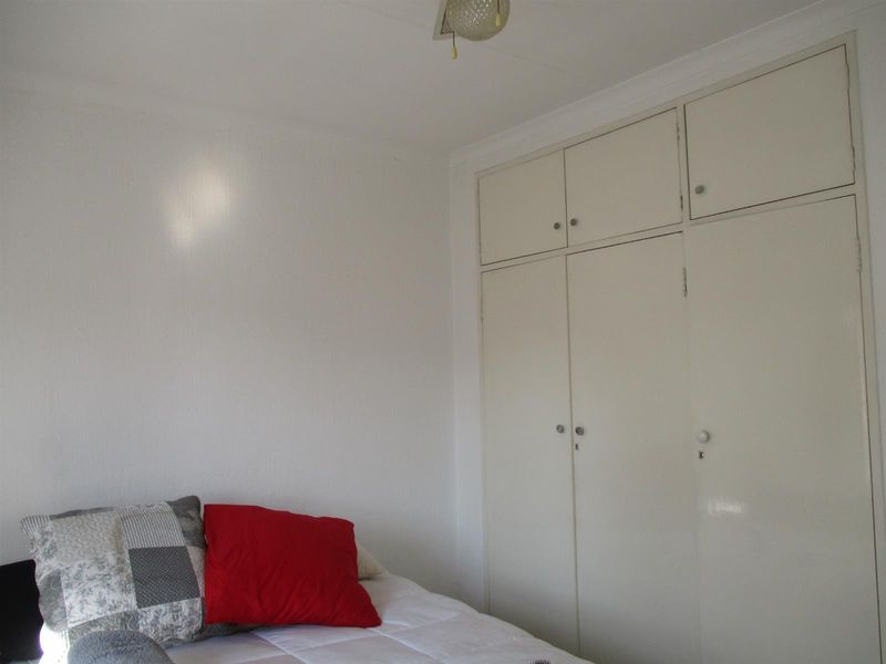 A bedroom featuring white walls and floor-to-ceiling built-in cupboards providing ample storage space.