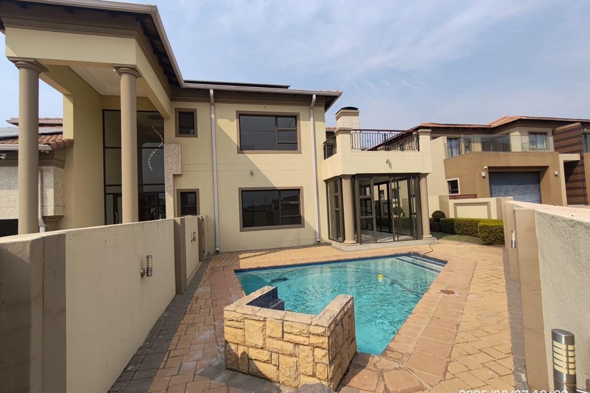 Rear view of the property featuring a swimming pool, paved patio area, and a balcony accessible from the upper level.
